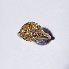 A rounded, slightly puffy shape made of ultra-lacy, modern take on filigree, less rigid than actual honeycomb; with 5 diamonds running horizontally from one end to the other