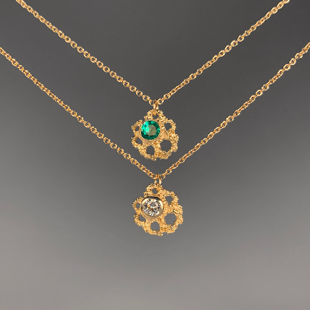 Textured, fan-shaped necklace with negative space and off-center bezel with stone; two necklaces shown, one with an emerald and one with a diamond