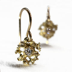 Lacy, textured, star-like earring on wire has center stone; shown here with white diamond