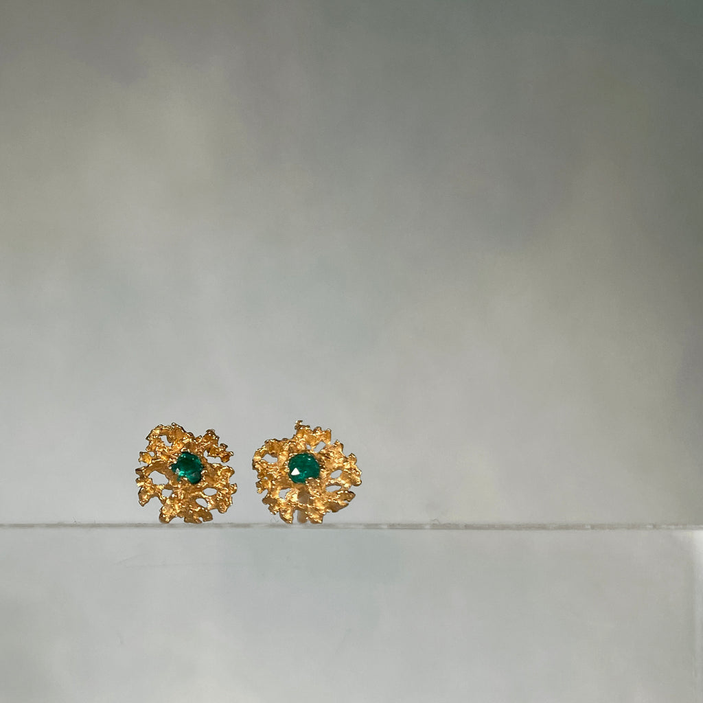 Lacy, textured, star-like stud earring has center stone; shown here with emerald