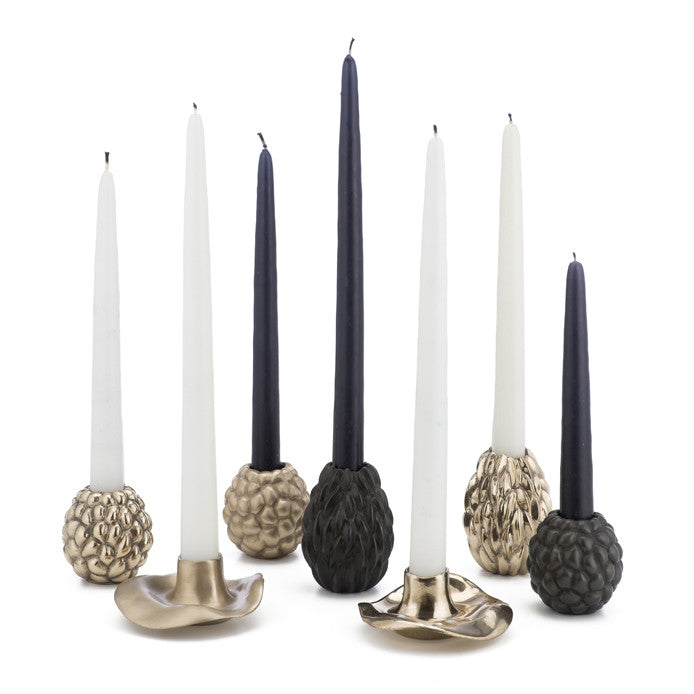 Group of various solid bronze candle holders, shown in various finishes and with candles