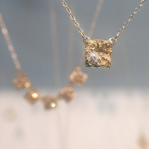 Thick, textured square pendant with diamond in 1 corner; shown in polished gold