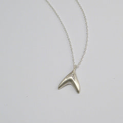 Fishtail-like pendant with arch of 5 diamonds following the shape; shown in matte silver