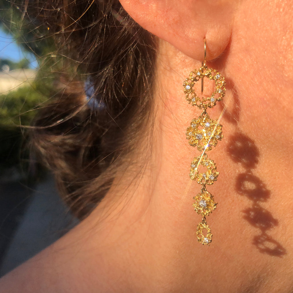 5-part wire earring made of various textured, diamond-studded shapes with negative space, and connected in order from largest at top to smallest at bottom