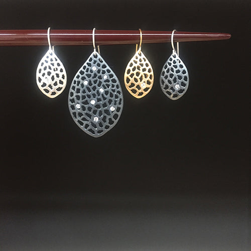 Variations of a leaf-shaped earring with lacy negative space: available in satin or blackened silver, or gold, and with 1 diamond or several