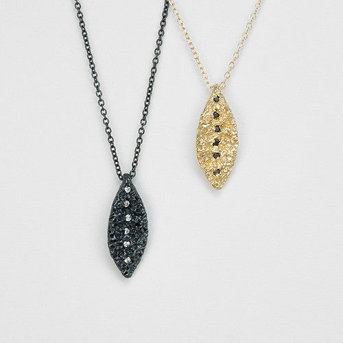 Textured, leaf-like shape with line of diamonds running top to bottom; shown in blackened silver with white diamonds and yellow gold with black diamonds