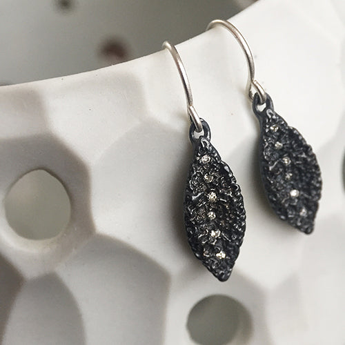 Textured, leaf-like shape with line of diamonds running top to bottom; shown in blackened silver with white diamonds