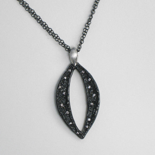 Large, textured, blackened, marquise shape with opening in middle, connected to smaller, silver marquise shape; white diamonds scattered throughout