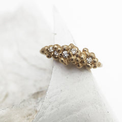 Cluster of tiny buds on top of band; set with white diamonds and shown in yellow gold