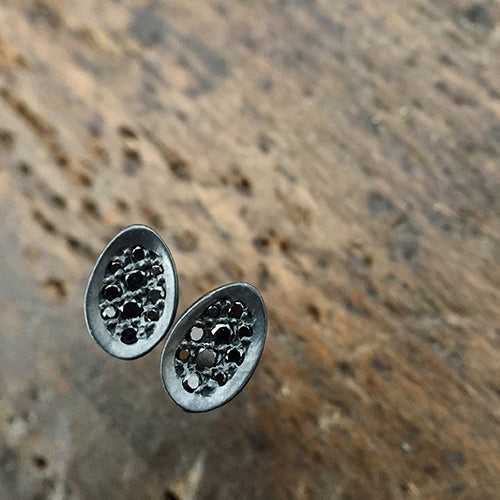 Tiny concave egg-shaped stud with pavé diamonds; shown in blackened silver with black diamonds
