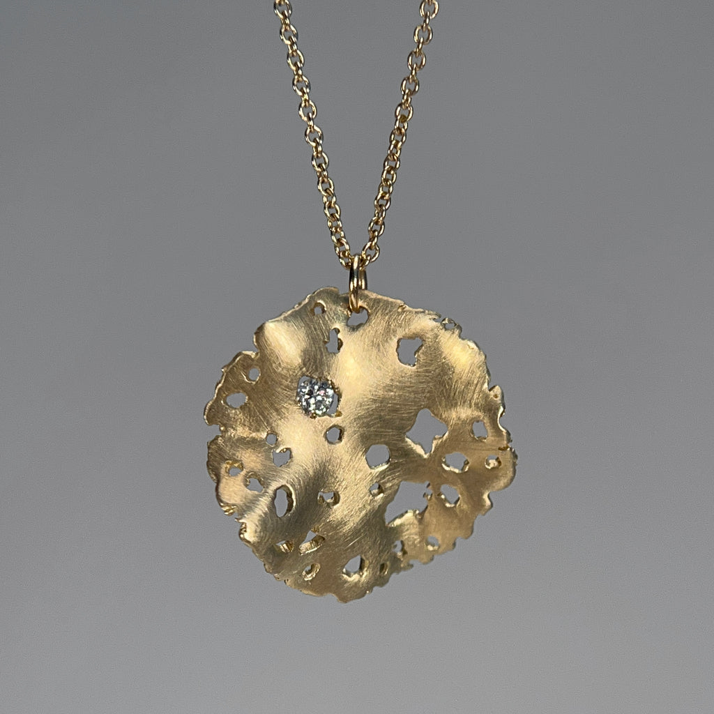 round ruffled pendant with textured edges and jagged holes and 1 white diamond; shown in 14k yellow