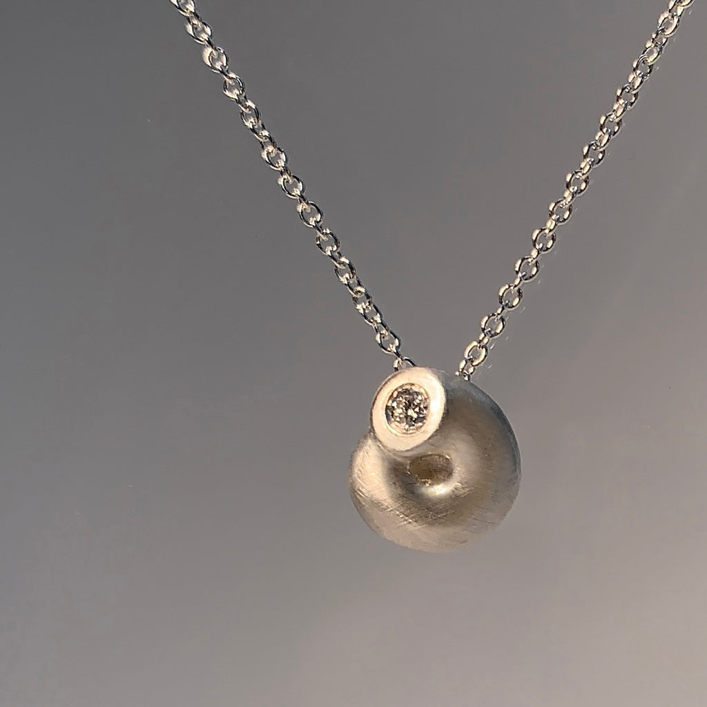 small, snail-like shape, with a flush-set diamond at one end of the piece