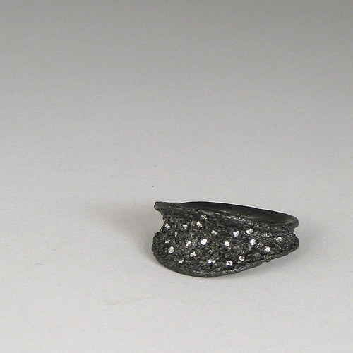 Concave, textured, leaf-shaped ring widens at top and edges flare upward; tiny diamonds are sprinkled in the valley of the leaf shape