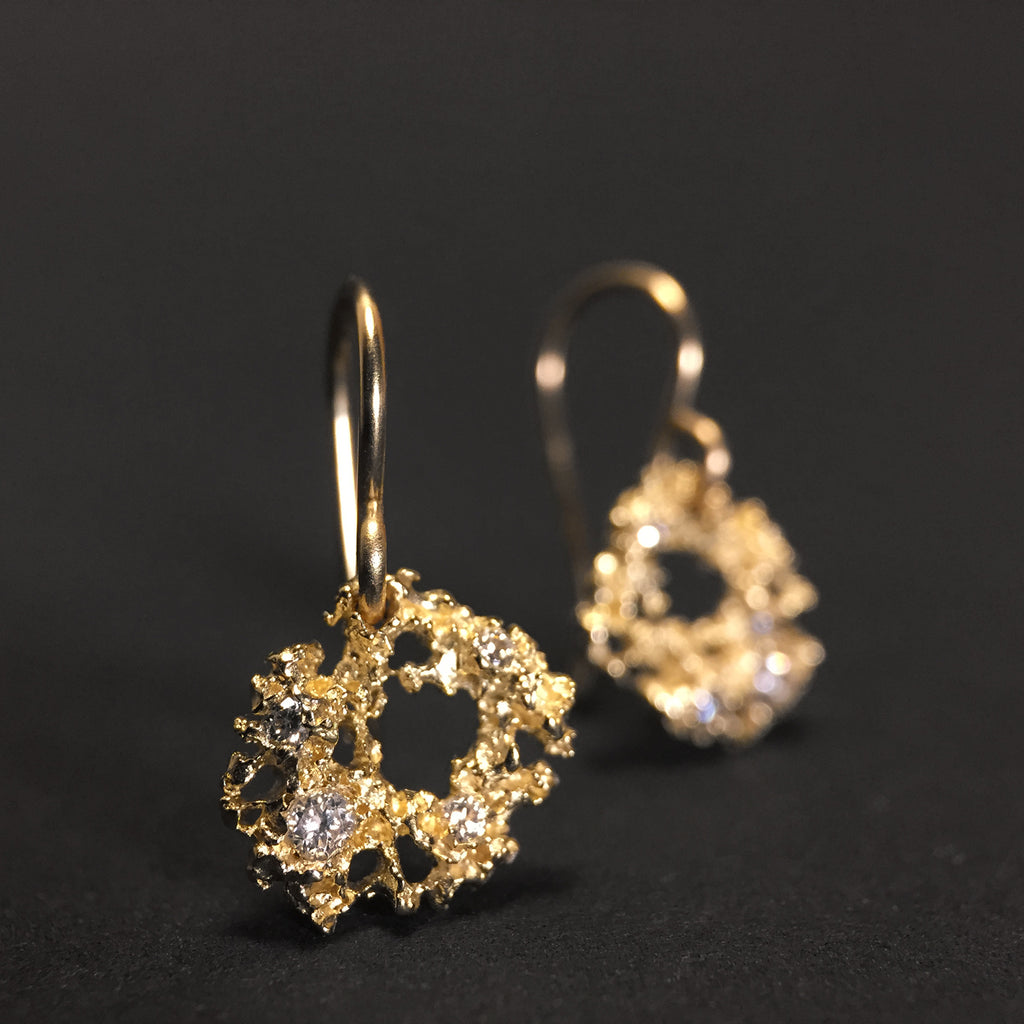 Amorphous, organic-shaped, textured, lacy earring on wire with large negative space in center; studded with diamonds