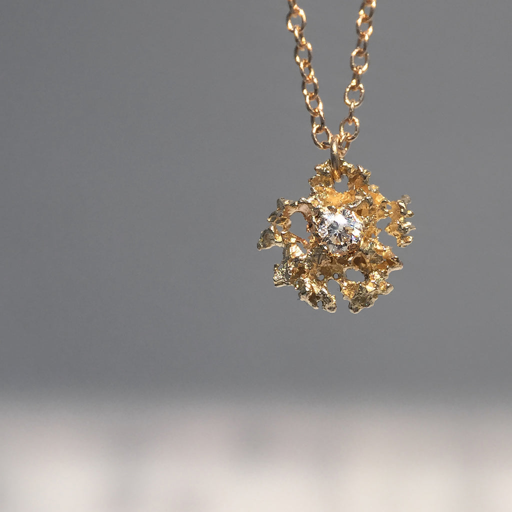 Lacy, textured, star-like pendant has center stone; shown here with white diamond