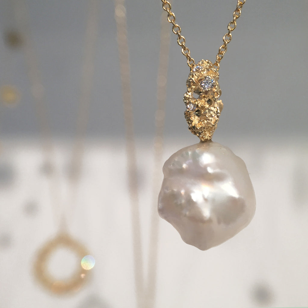 Imperfectly shaped pearl with textured, lacy bail studded with diamonds