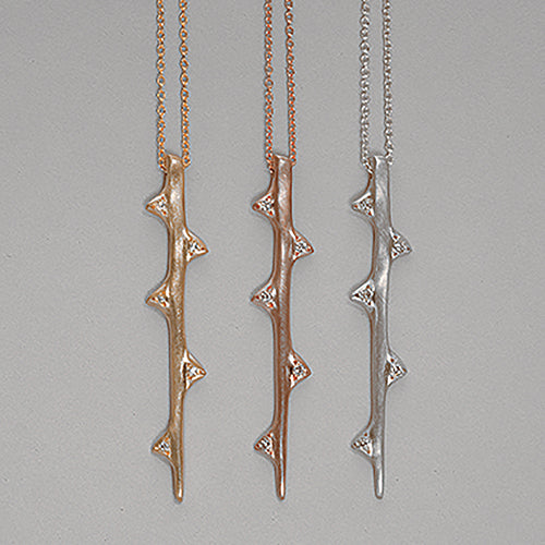 Stylized branch with 5 thorns, 3 on one side and 2 on the other, each with a diamond in the center; hangs vertically; shown in silver, yellow gold, rose gold