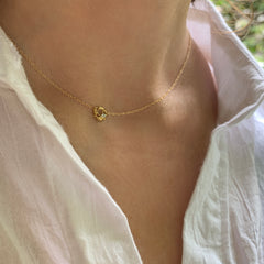 Lacy, textured, tiny element on chain, with white diamond set off-center; shown on neck