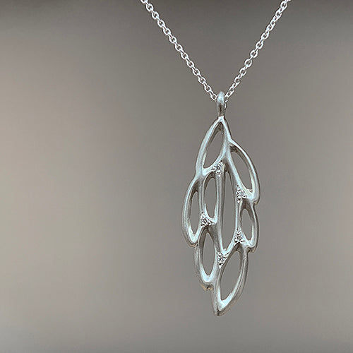 Wing-shaped pendant has cutouts resembling the pattern of a moth wing; studded with 5 diamonds