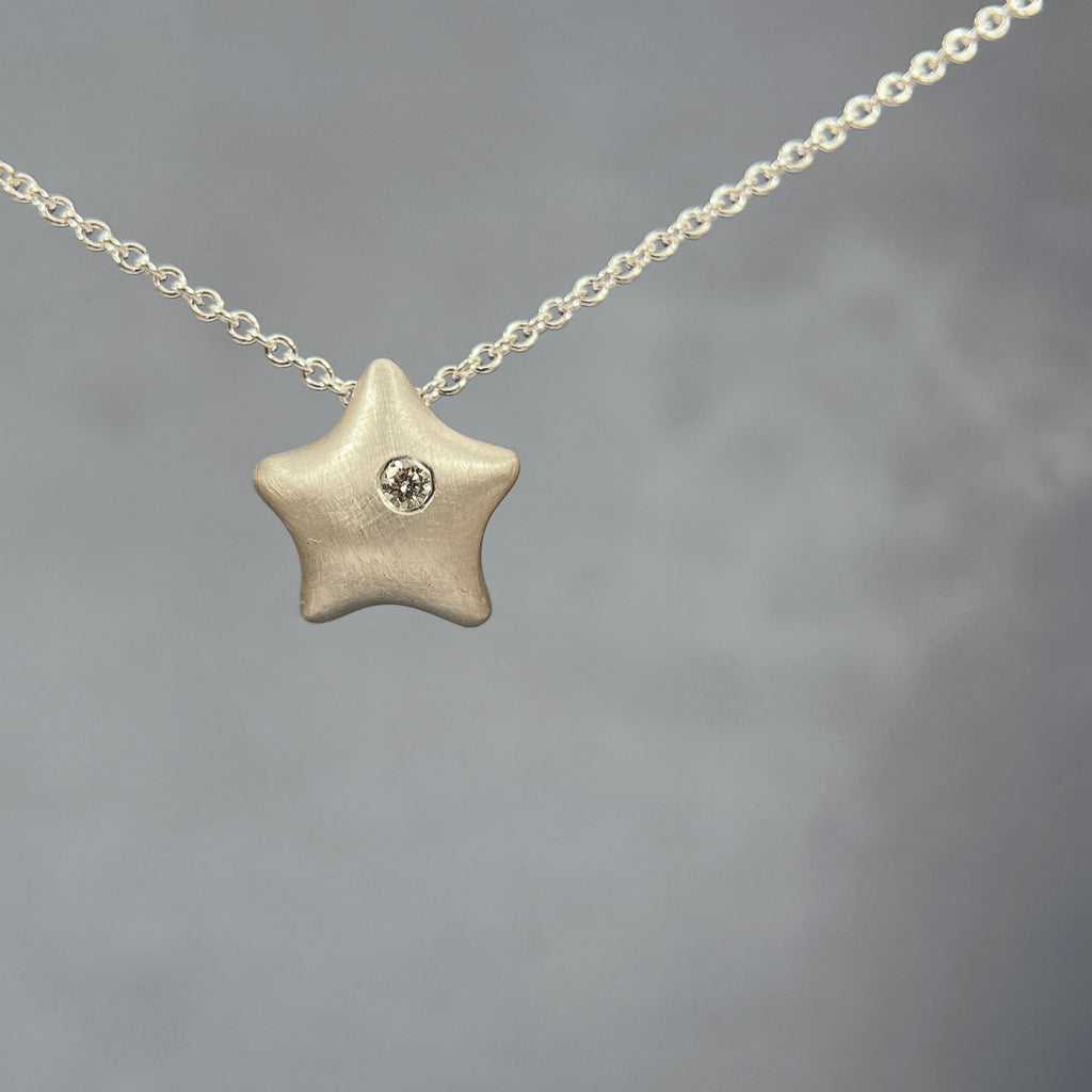 small, minimal, soft, and puffy starfish with hidden bail on back and one flush-set 2 pt diamond