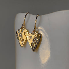 Flat but slightly thick heart with negative spaces, one of which holds a stone; shown in polished gold with diamonds