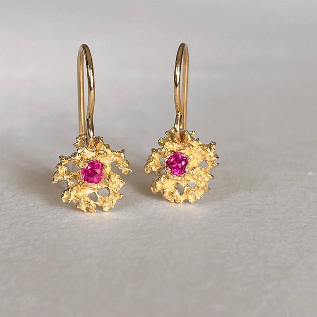 Lacy, textured, star-like earring on wire has center stone; shown here with ruby 