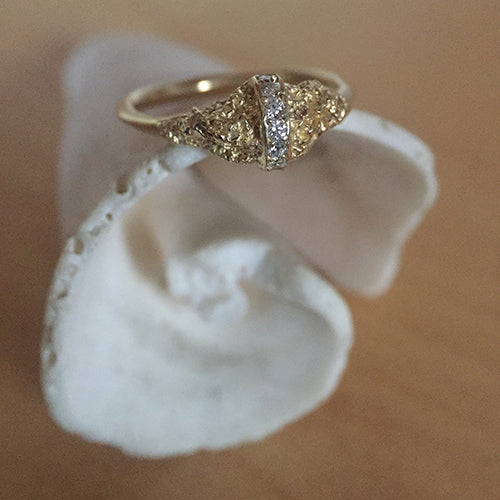 A ring with a textured moutain, bissected by a diamond strip; remainder of band in thin and polished