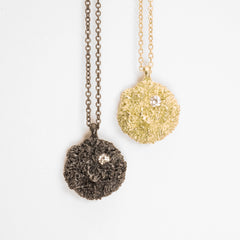 Textured mushroom-like puff with diamond in top right quadrant; shwon in polished gold and blackened silver