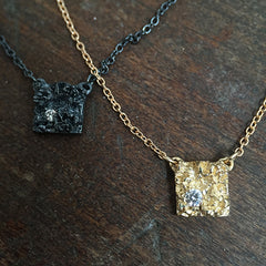 Thick, textured square pendant with diamond in 1 corner; shown in blackened silver and polished gold
