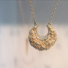 Textured and polished crescent moon pendant with diamonds in inner curve; shwon in polished gold