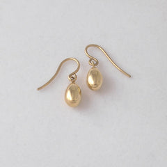Shiny, solid egg earrings on wires, shown here in yellow gold
