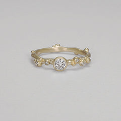 Organic ring resemblic a branch. Large center stone with three delicate diamond buds on either side. Shown in yellow gold.