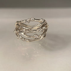 Organic, branch-like ring with five branches crisscrossing and thirteen tiny diamond buds. Shown in silver.