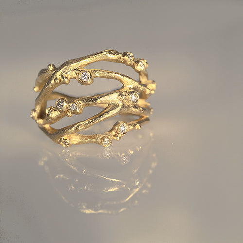 Organic, branch-like ring with five branches crisscrossing and thirteen tiny diamond buds. Shown in yellow gold.