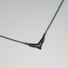 Elongated Fishtail-like pendant with arch of 5 diamonds following the shape; shown in blackened silver