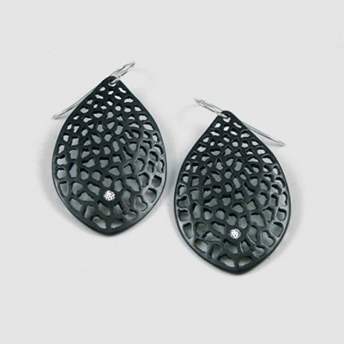 leaf-shaped, slightly convex earring on wire; has overall pattern made by organic cutouts; shown in blackened silvet with a white diamond in the center, toward the bottom of the piece