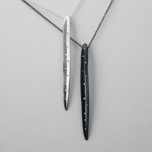 Long, slightly concave, leaf-like shaped pendant with scattered small diamonds in various sizes; shown in matte and blackened silver options