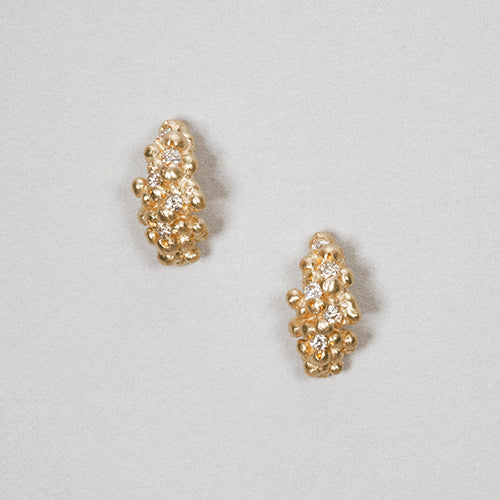 Cluster of tiny buds in shape that curls just under the ear lobe; set with white diamonds and shown in yellow gold