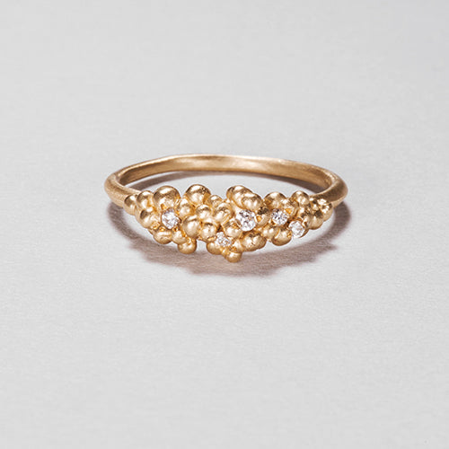 Cluster of tiny buds on top of band; set with white diamonds and shown in yellow gold
