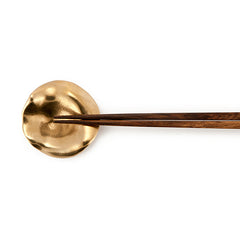 Cast bronze piece with concave center portion and ruffled, undulating outer area; shown as a chopstick rest