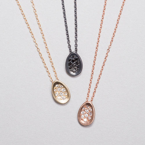 Tiny concave egg-shaped pendant with pavé diamonds; shown in 14k yellow, 14k rose, and blackened silver
