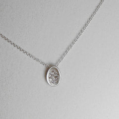 Tiny concave egg-shaped pendant with pavé diamonds; shown in matte silver