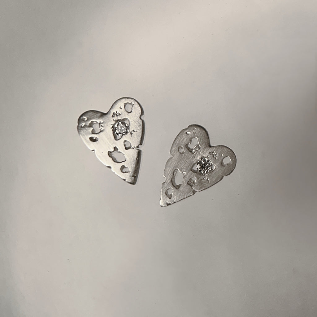 silver heart stud with a white diamond; satin finish with jagged holes