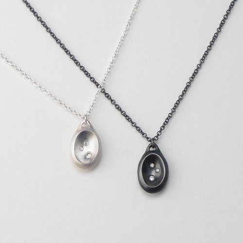 Oval, concave pendant with three diamonds