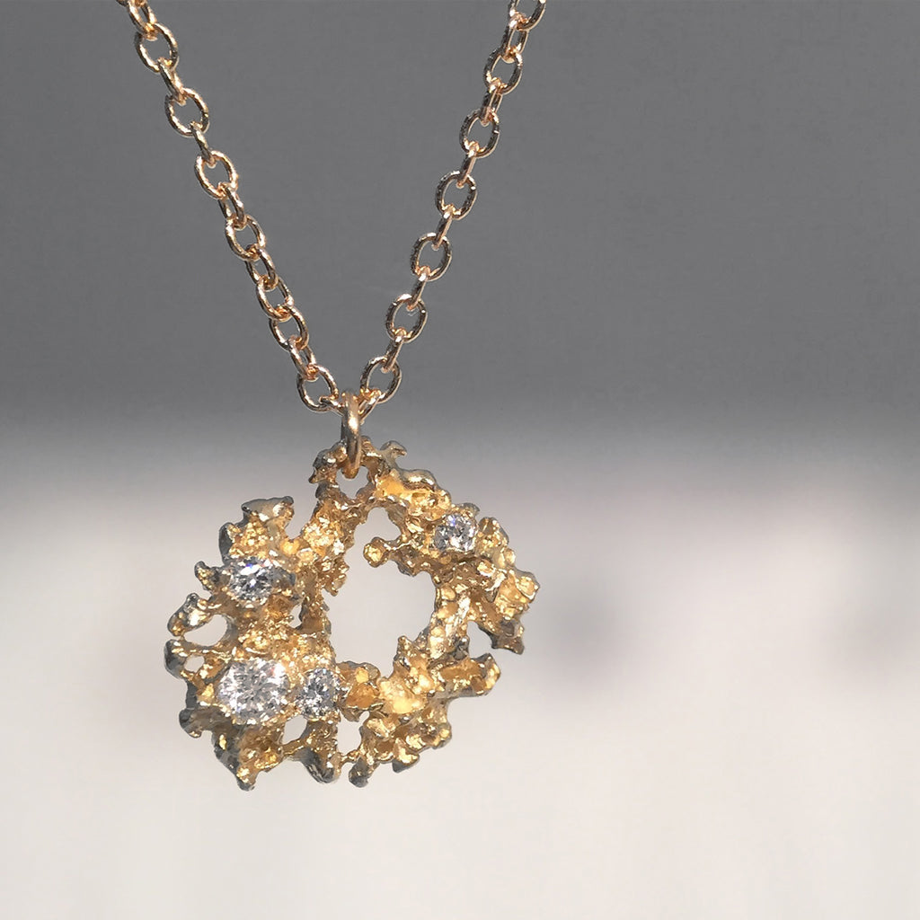 Amorphous, organic-shaped, textured, lacy pendant with large negative space in center; studded with diamonds