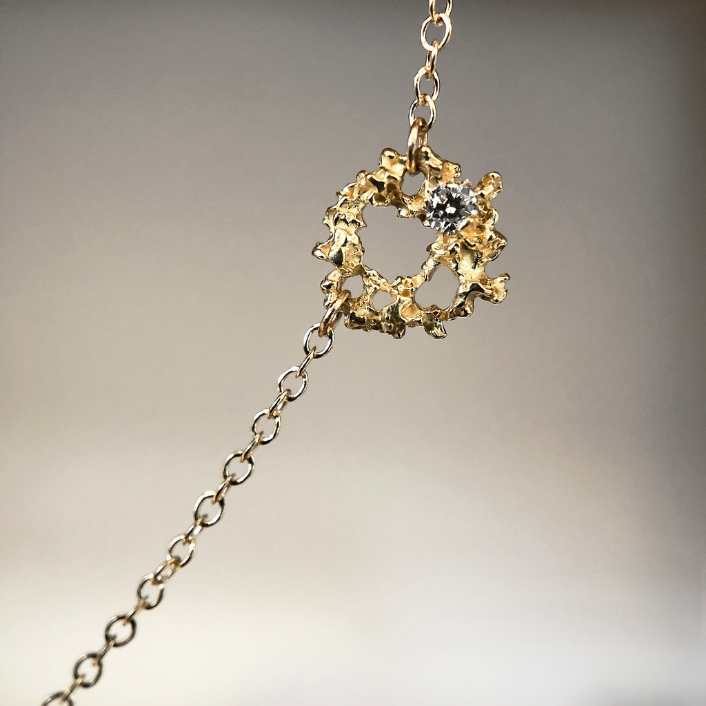 Lacy, textured, tiny element on chain, with white diamond set off-center