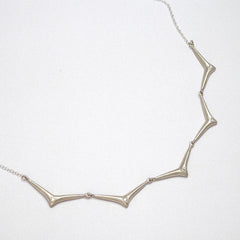 Necklace comprised of 5 components connected to each other and to chain, forming a collar of soft, elongated, stylized thorny branches, each with a center diamond; shown in satin silver